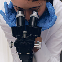 A clinician looking through a laboratory microscope