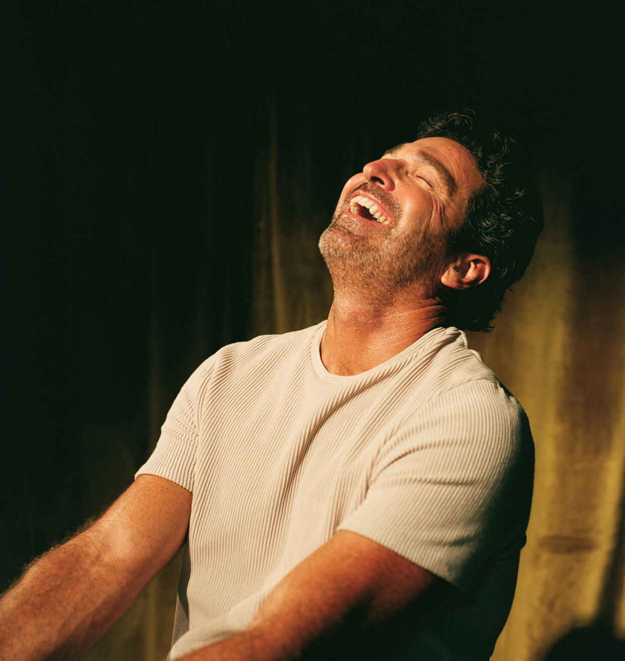 A patient laughing, head tilted back, in warm low light