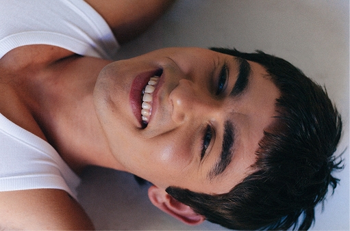 A person arched into a backbend against a sand-colored backdrop
