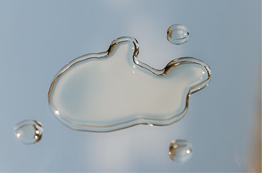 A pool of water beaded on a pale blue surface