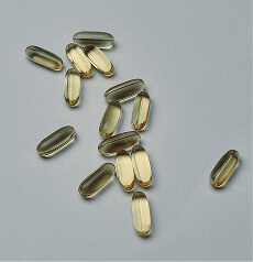 Amber softgel capsules scattered on a pale gray surface