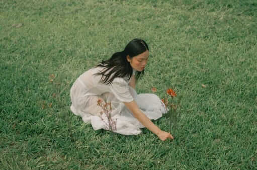A woman in a white dress sitting on a bright green lawn