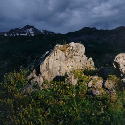 A rocky outcrop below a dark mountain ridge