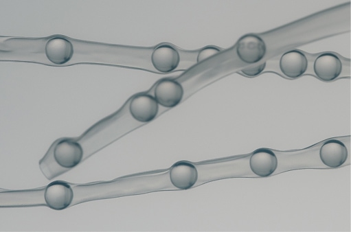 A glass petri dish holding clear droplets on a warm sand surface
