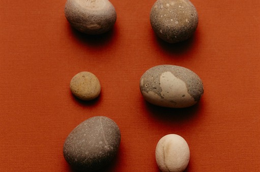 Six smooth river stones laid out on burnt orange