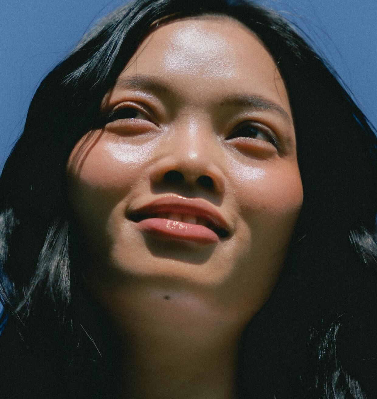A woman looking up into the light against a deep blue sky