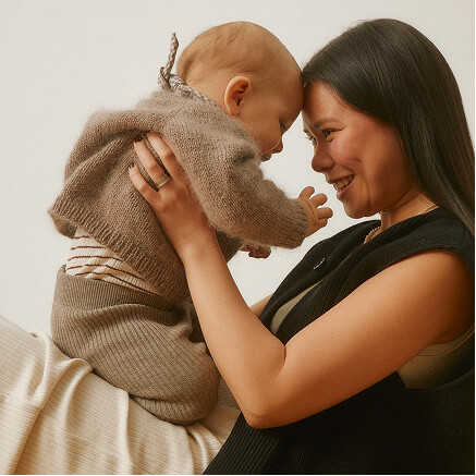 A mother laughing with her baby held close, foreheads touching