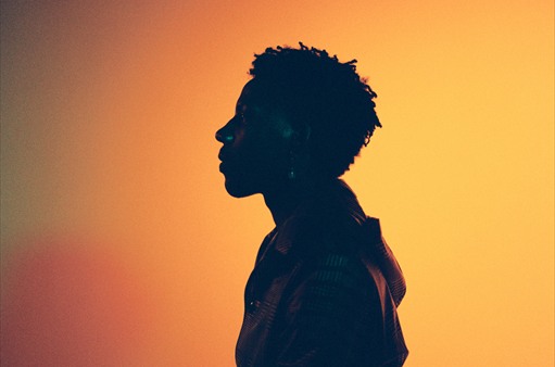 A person in profile silhouetted against a warm orange gradient