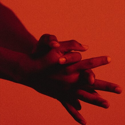 Two hands overlapping, lit deep red against a red ground